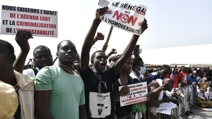 Des manifestants brandissent des pancartes lors d'une manifestation le 20 février 2022 sur la place de l'Obélisque à Dakar, réclamant un durcissement de la répression contre l'homosexualité. (SEYLLOU / AFP)