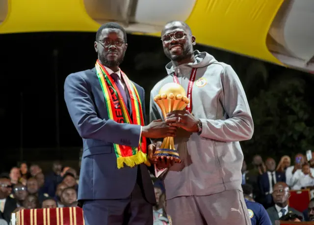 Le président Bassirou Diomaye Faye du Sénégal et le capitaine Khalidou Koulibaly célèbrent ensemble avec le trophée de la CAN 2025