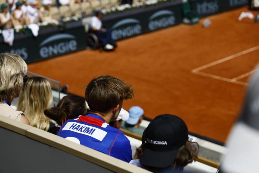 Quelques supporters du PSG agitant des écharpes aux couleurs du club dans les gradins de Roland-Garros.