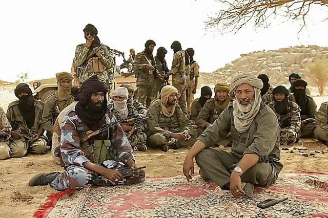 Combattants touaregs en discussion sous un arbre dans le désert