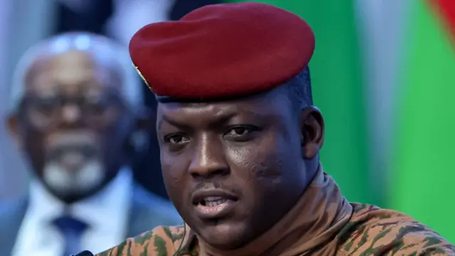 Portrait du capitaine Ibrahim Traoré portant un béret rouge et une tenue militaire beige.